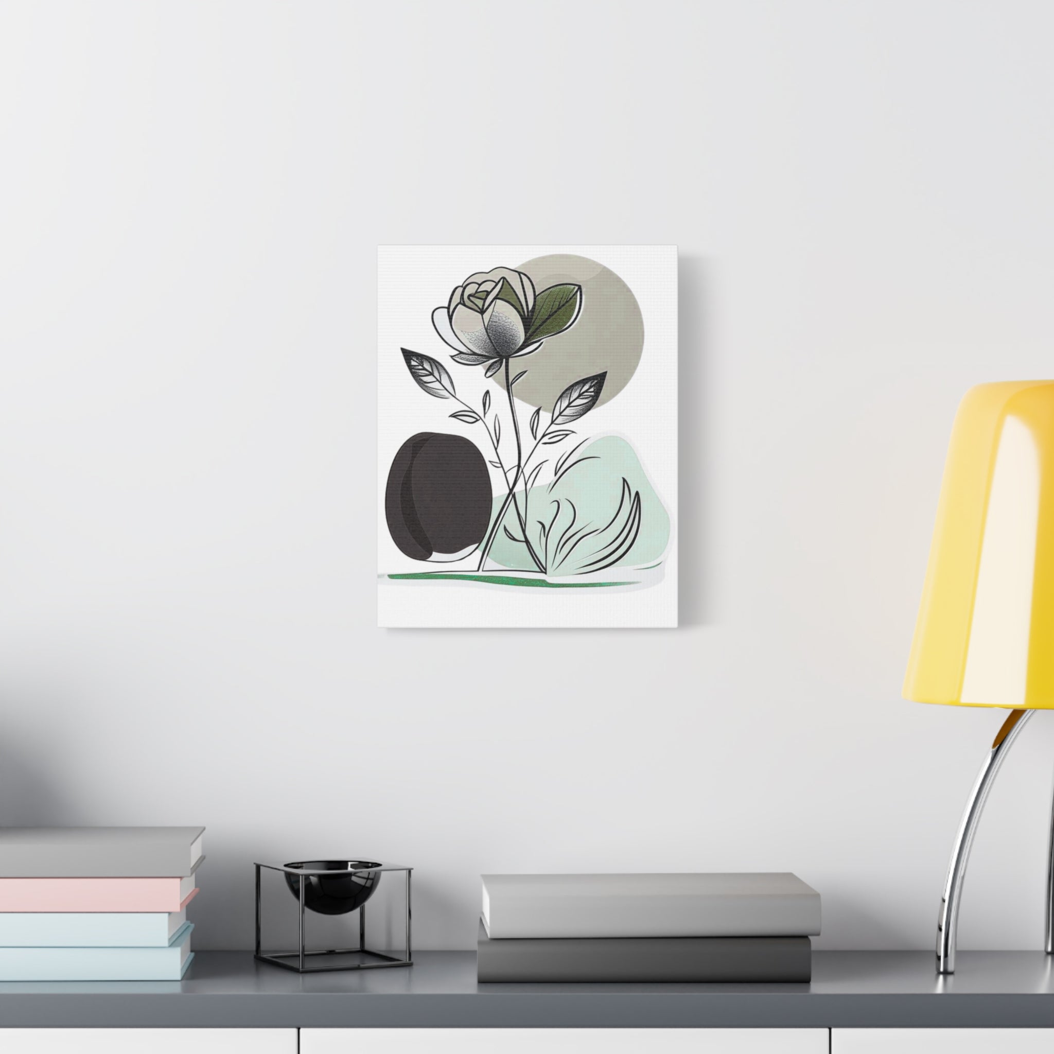 Framed artwork of a rose on a wall above a desk with books and a lamp.