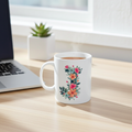 White mug with floral design on a wooden desk next to a laptop