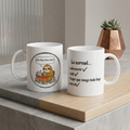 Two white mugs with humorous designs on a wooden surface.